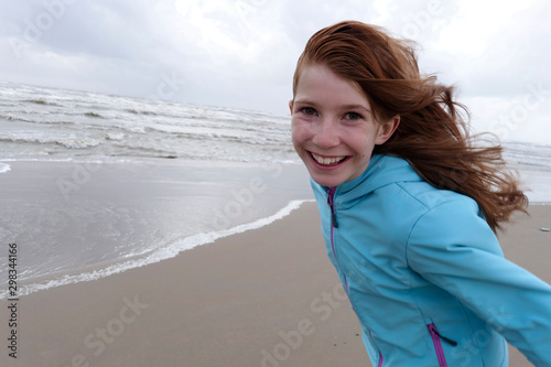 Portrait of smiling redheaded girl on a windy day on the beach photo