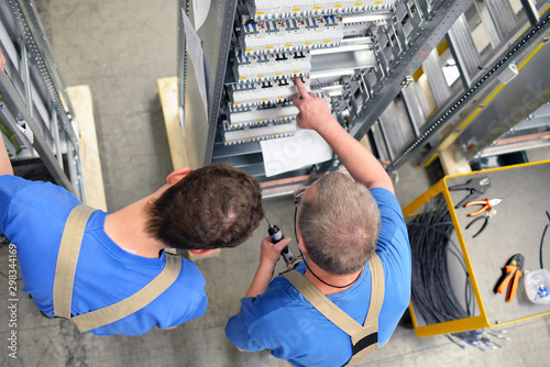 Two workers in a switchboard construction factory