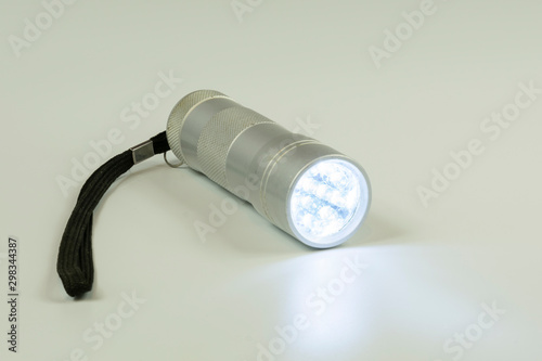 pocket metal flashlight with burning LEDs on a white background