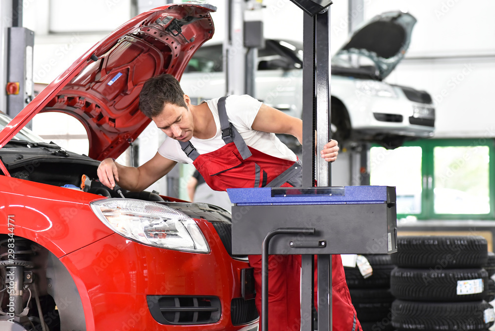 Car mechanic working in repair garage, setting car headlights Car mechanic working in repair garage, setting car headlights