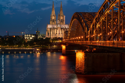 Cologne cathedral and Hohenzollern Bridge over Rhine river at dusk