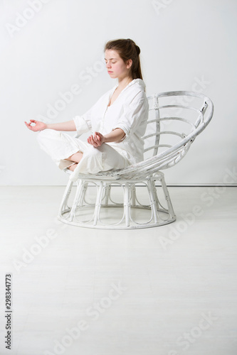 Teenage girl exercising yoga position in white room photo