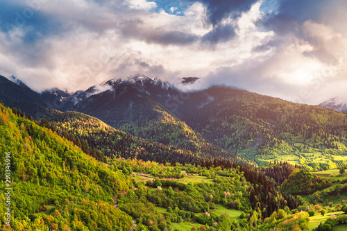 Beautiful sunset in the Caucasus Mountains. Green meadows, forests and sun rays.