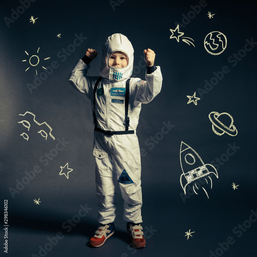 Child with spacesuit orbited by celestial bodies and luminaries photo