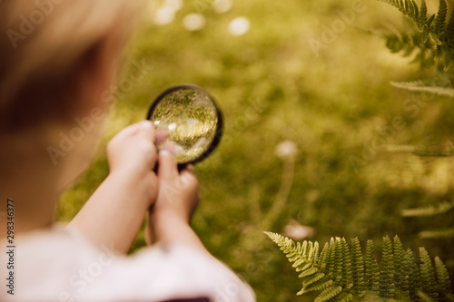 Boy looking through magnifier on fern leaf