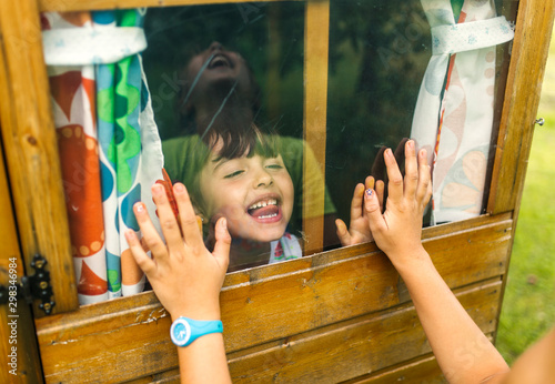 Spain, Asturias, Gijon, Little girls playing through a glass window photo