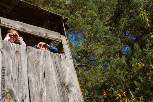 Boy and girl in tree house looking at distance photo