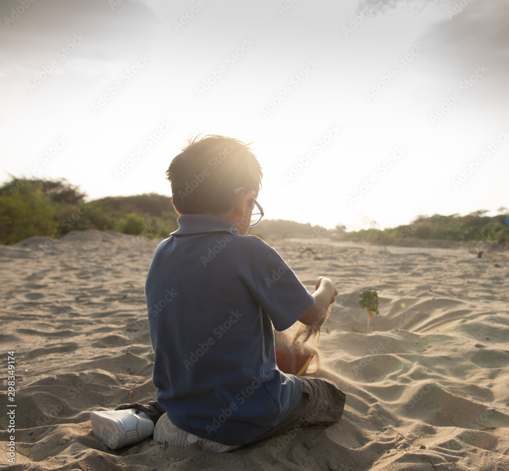 Child plays with sand at sunset in summer Child plays with sand at sunset in summer
