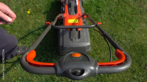 Wallpaper Mural Slow motion POV shot of a man fitting a grass collection box, then pushing the start button on a modern, lightweight, cordless (battery operated) garden lawnmower, then beginning to push it on grass. Torontodigital.ca