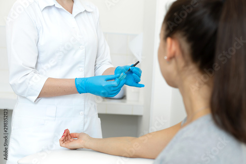 a gloved nurse removes a sterile needle from its packaging in front of the patient. Blood sampling procedure
