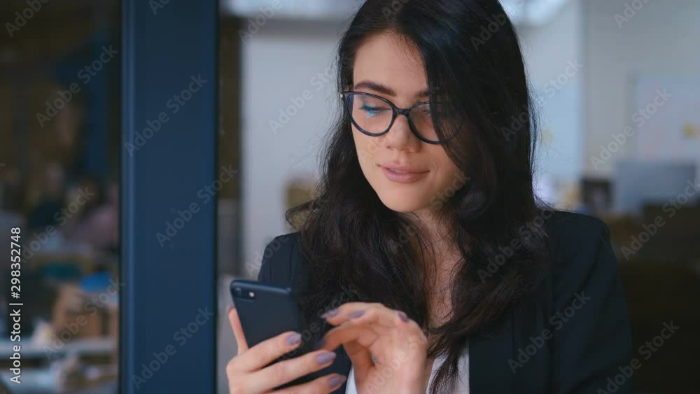 Portrait of Beautiful Young Woman Using Smartphone in Office. Business Lady in Formal Wear Dress Typing Messages on her Mobile Phone.