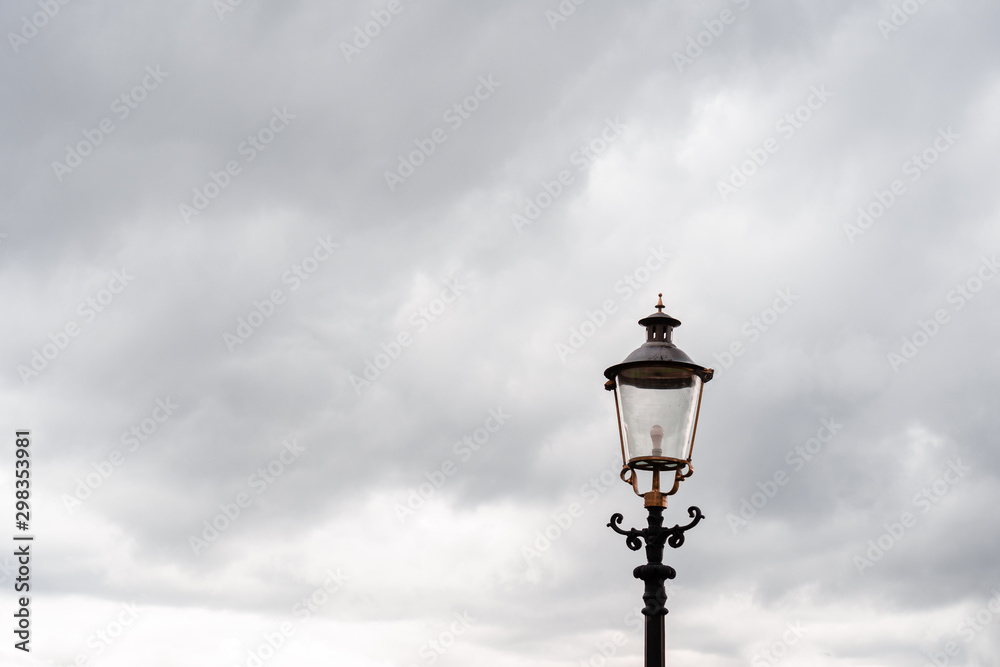 Street lantern, top. Against the background of heavy autumn gray sky with gray rain clouds. Horizontal orientation.
