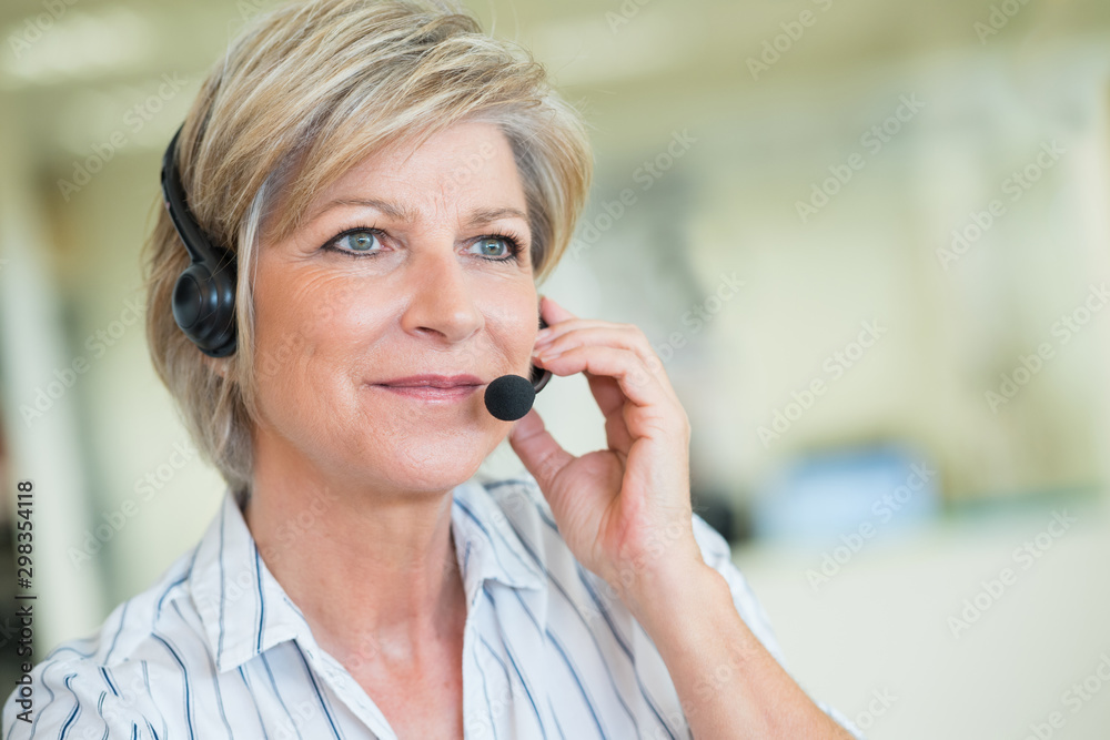 mature female customer-services worker wearing headset - obrazy, fototapety, plakaty 