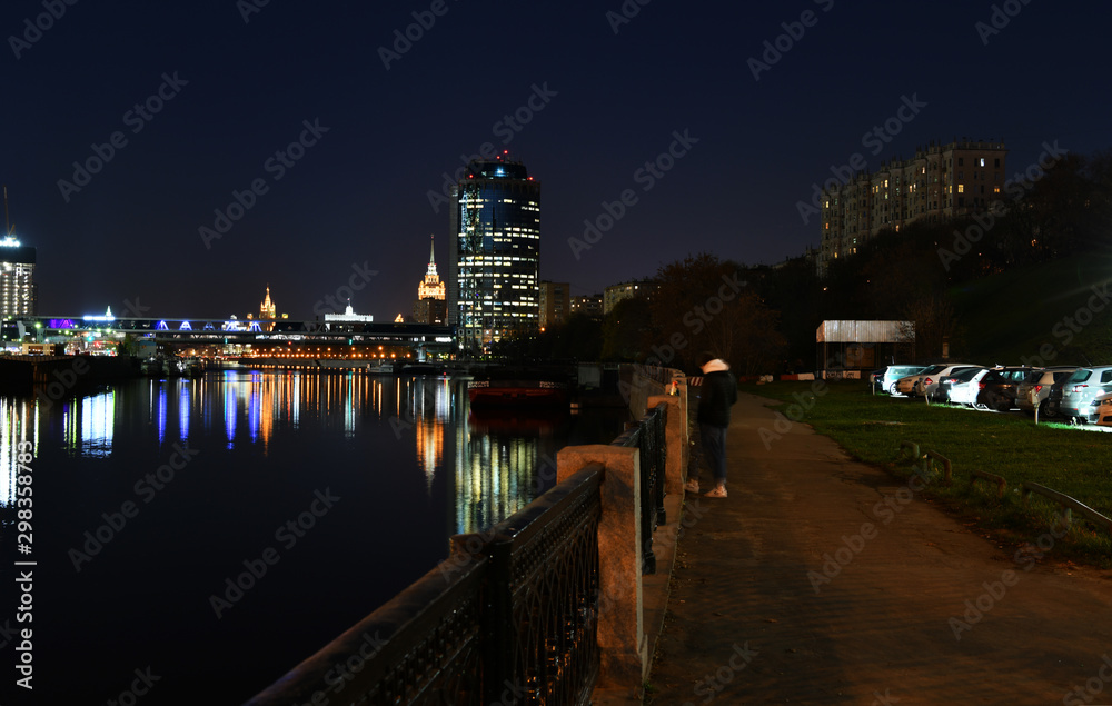 brightly lit tall buildings at night and reflected in the river
