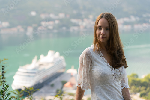 girl posing on the background of the city of Kotor and a cruise liner