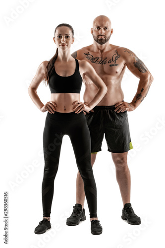 Athletic man in black shorts and sneakers with brunette woman in leggings and top posing isolated on white background. Fitness couple  gym concept.