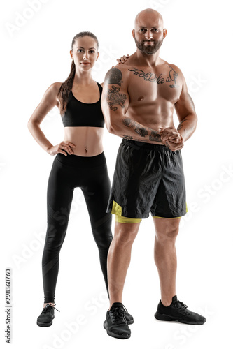 Athletic man in black shorts and sneakers with brunette woman in leggings and top posing isolated on white background. Fitness couple, gym concept. © nazarovsergey