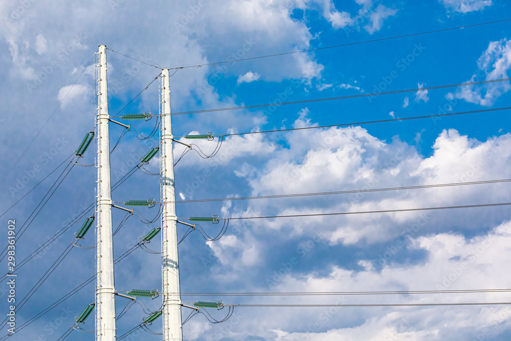 Two utility poles are viewed from below, supporting overhead electric ...