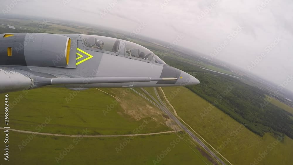 A gray blue combat plane fly over a road in field and rolls to the left. A fighter moves over a green forest against a thundercloud in dark sky. View from the right wing close up. A gray blue combat plane fly over a road in field and rolls to the left. A fighter moves over a green forest against a thundercloud in dark sky. View from the right wing close up.