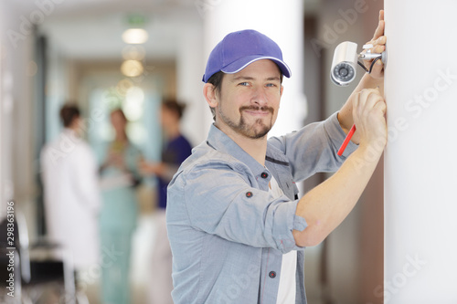 happy male technician fixing a cctv camera inside hospital