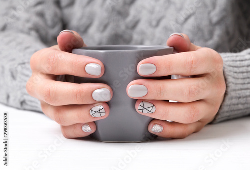 Woman's hands with geometric manicure nail design in cozy sweater