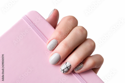 Females hand with modern manicure holds pink notepad close up