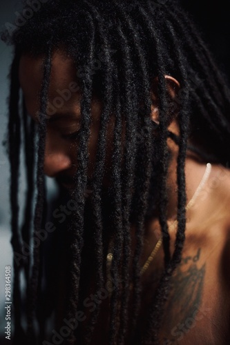 Portrait of man with tattoo on chest displaying dreadlocks