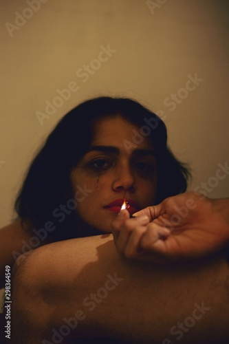 Direct view of woman getting cigarette lit while resting her chin on a thigh