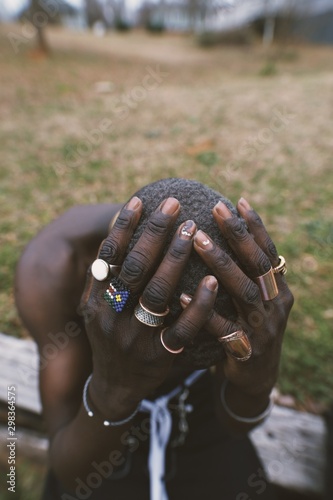 Close up of man holding ringed hands on head