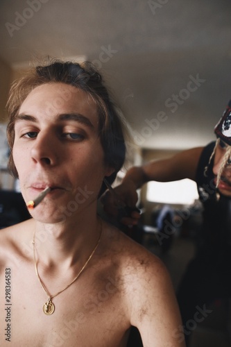 Portrait of young man smoking and getting haircut at barber shop