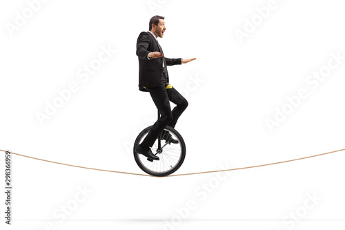 Excited young businessman riding a unicycle on a rope photo