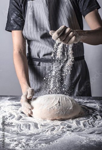 Posypywanie ciasta bochenka chleba mąką osoba w fartuchu piekarz