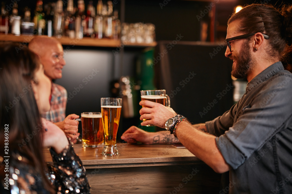 Friends standing next to bar counter in pub and drinking beer. Night out. Friends standing next to bar counter in pub and drinking beer. Night out.