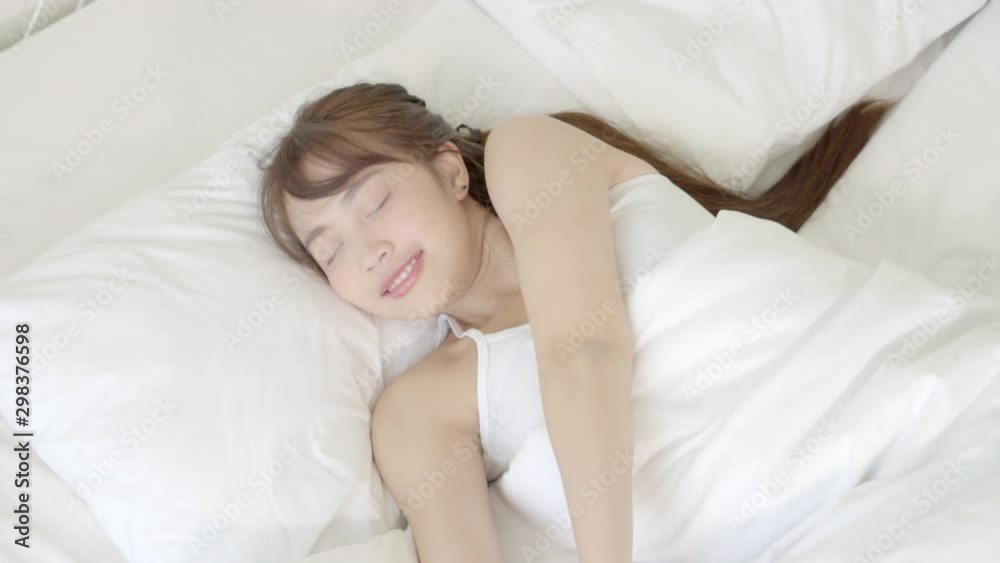 Beautiful young asian woman waking up in the morning and stretching and gets up sitting on bed in the bedroom, girl sleep cozy and wake with fresh happy and smile, wellbeing and health concept. Beautiful young asian woman waking up in the morning and stretching and gets up sitting on bed in the bedroom, girl sleep cozy and wake with fresh happy and smile, wellbeing and health concept.