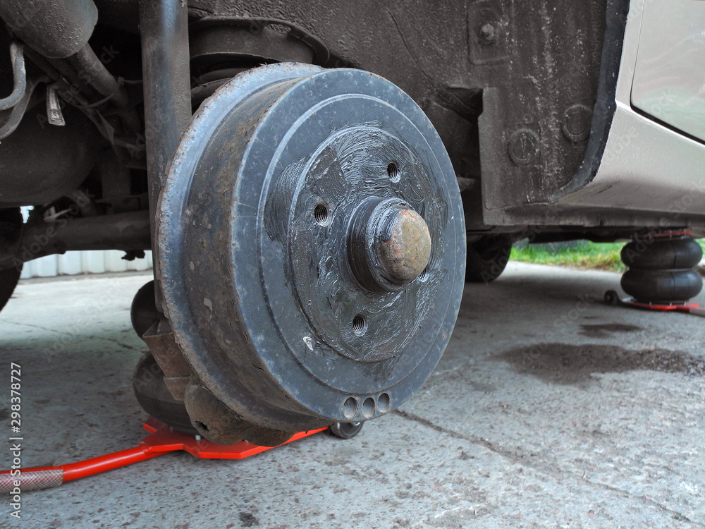 Car on tire mounting with removed wheel on pneumatic jack. Wheel hub closeup. Seasonal tire change. Breakdown wheel. Car service concept. Car on tire mounting with removed wheel on pneumatic jack. Wheel hub closeup. Seasonal tire change. Breakdown wheel. Car service concept.
