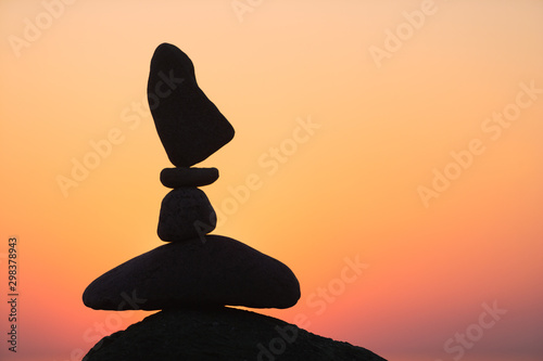 Canvas Print balanced stones on the beach at sunset