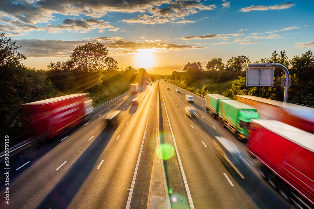 heavy traffic moving at speed on UK motorway in England at sunset - obrazy, fototapety, plakaty 