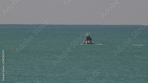 Police motor boat slowly turning, through blue mediterranean swell waves.
