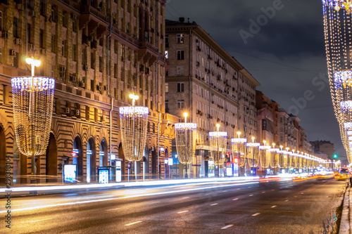 Street beautifully decorated with Christmas lights. The road goes beyond the horizon. Cars rushing at high speed. Center of Moscow on a winter evening.