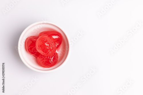 Maraschino cherry in a white bowl, isolated on white background, soft light, studio shot