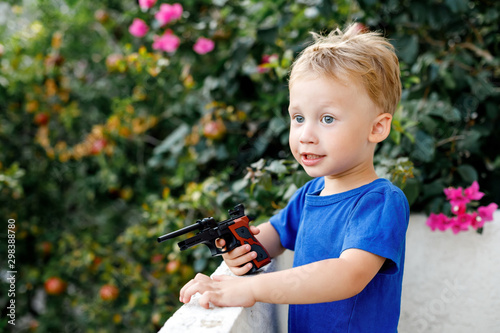 Cute kid boy with toy gun in garden background