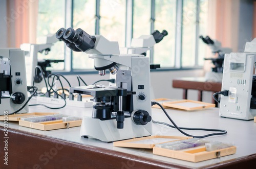 Microscope with micro plate on white table in laboratory setting for research and learning