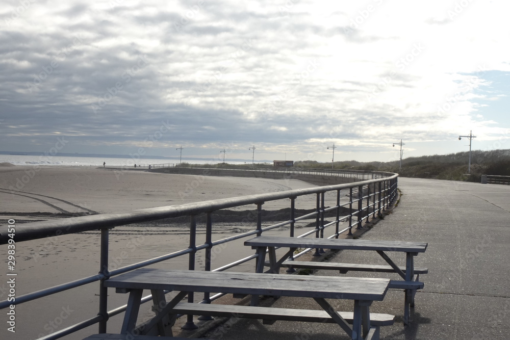 Sky, sand, sea, and boardwalk with tables and railings Sky, sand, sea, and boardwalk with tables and railings