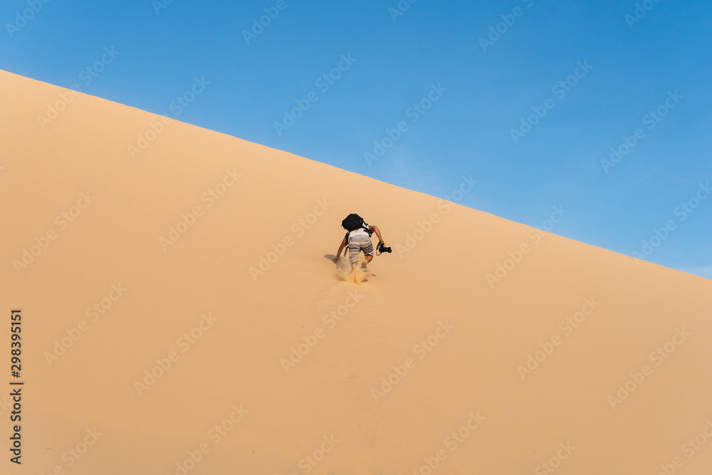 photographer climbing sand dunes in the desert