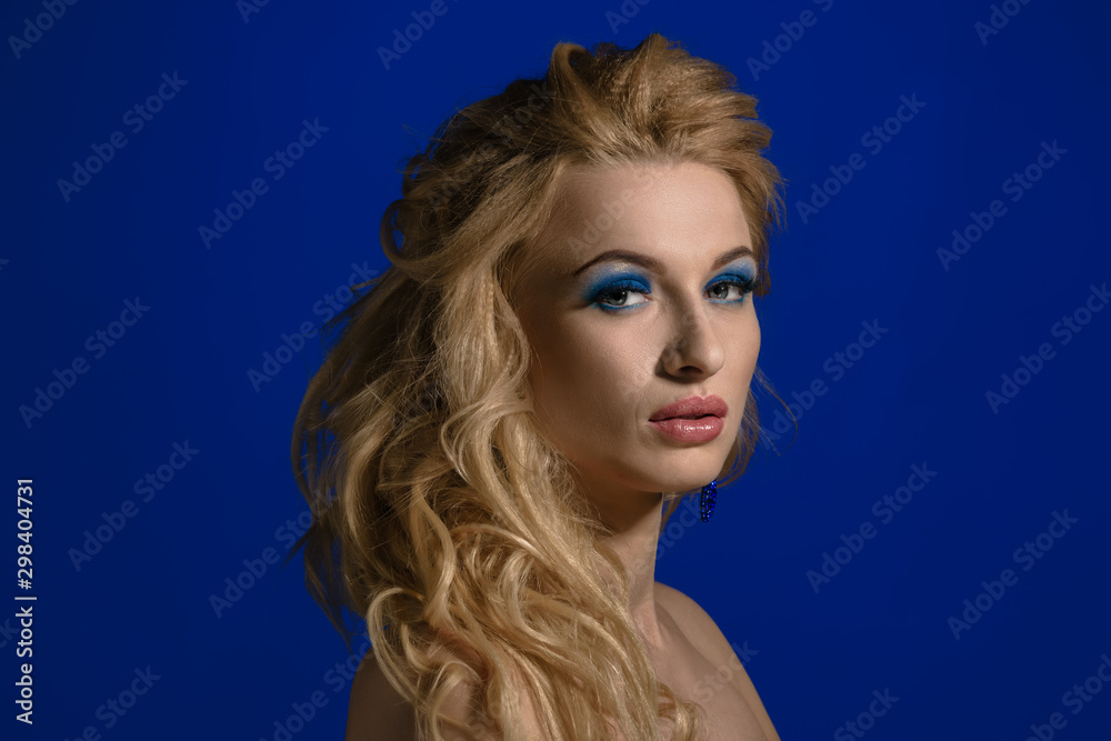 Beautiful blonde woman with long wavy hair on blue background Beautiful blonde woman with long wavy hair on blue background
