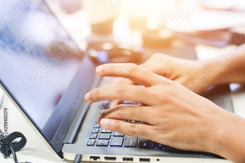 Close up fingers hands of businessman working using laptop keyboard on the table with sunlight, business technology background concept.