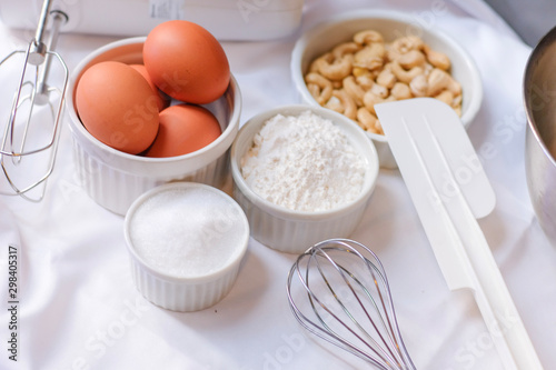 The process of making homemade sweet dessert bakery . Culinary equipment and ingredients. Eggs, flour, sugar, bakeware on white fabric in the kitchen