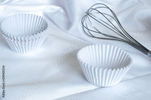 Empty cupcake mold White Paper baking cups for cupcakes and muffin bakeware on white fabric in the kitchen   The process of making homemade sweet dessert bakery  Preparation before baking cupcakes.