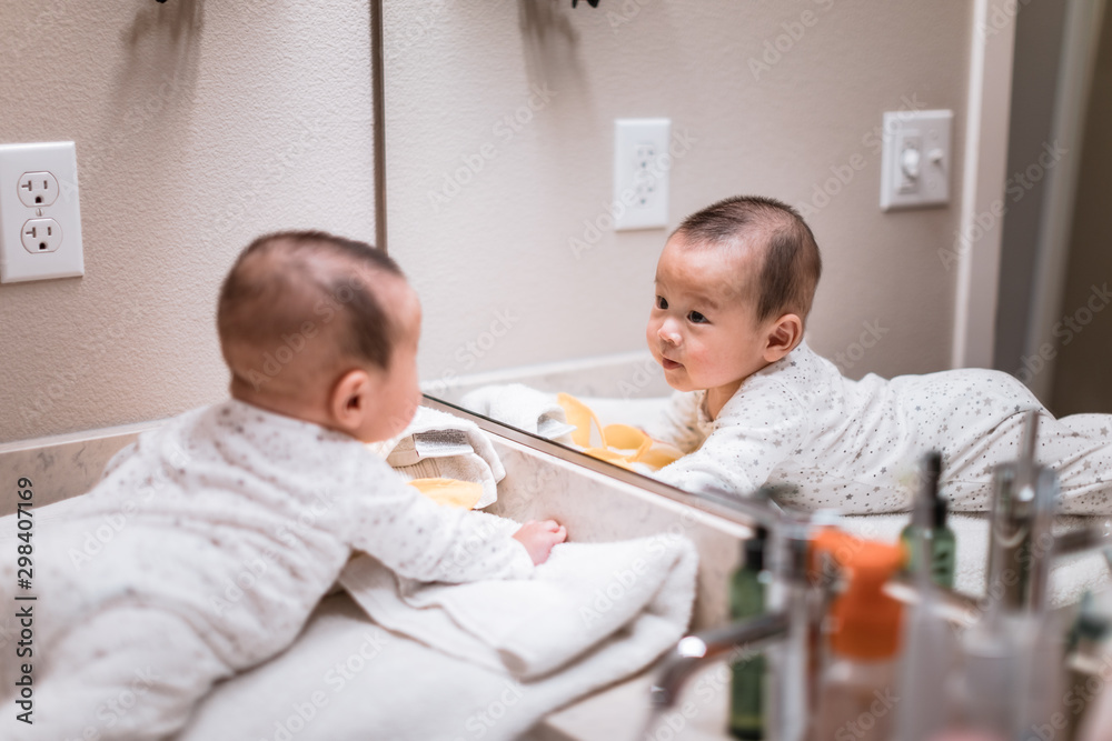 Obraz premium Adorable 5 month old asian baby boy in looking into bathroom mirror