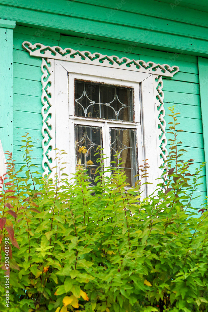 Fototapeta premium window with carved platbands in a green wooden house